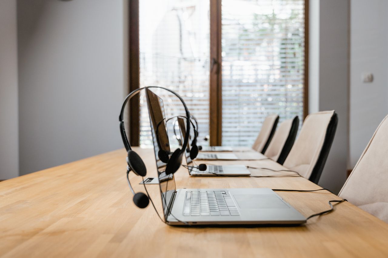 Modern conference room with laptops and headsets lined up ready for a meeting.